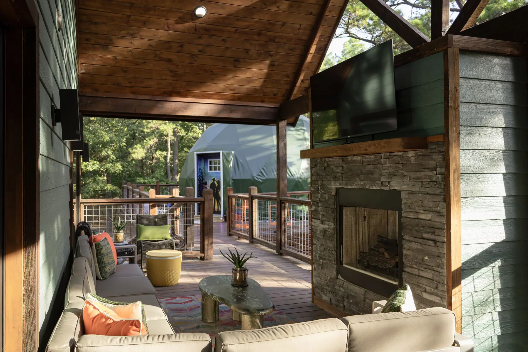 Covered outdoor living room with stone fireplace and TV