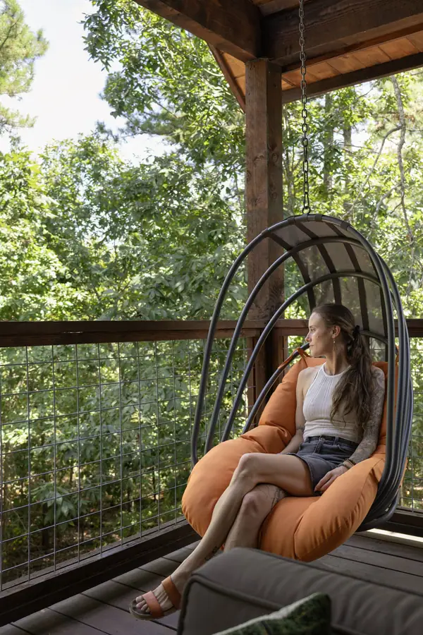 Guest relaxing in a hanging egg chair on the covered porch